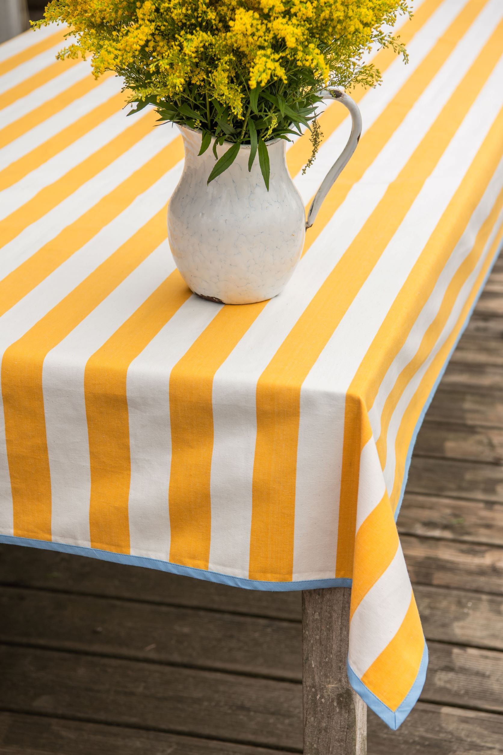 yellow striped tablecloth with blue edging – table in the sun